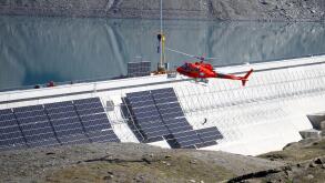A helicopter flies past the construction site of a large-scale photovoltaic system of Swiss energy provider Axpo at some 2500 metres above sea level on the dam of Lake Muttsee, Switzerland August 19, 2021. Picture taken August 19, 2021.   REUTERS/Arnd Wie