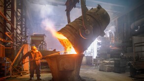 Steel worker and buckets of molten metal in steel foundry