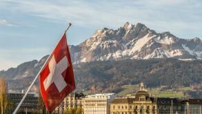 Swiss National Flag in Lucerne in Central Switzerland with the mountain range of Mt Pilatus in the background