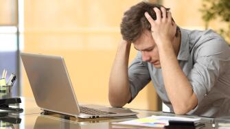 Worried businessman lamenting in front of a computer after a big mistake at office