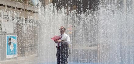 A man stands in a fountain on a sunny day on the South Bank in central London, Britain