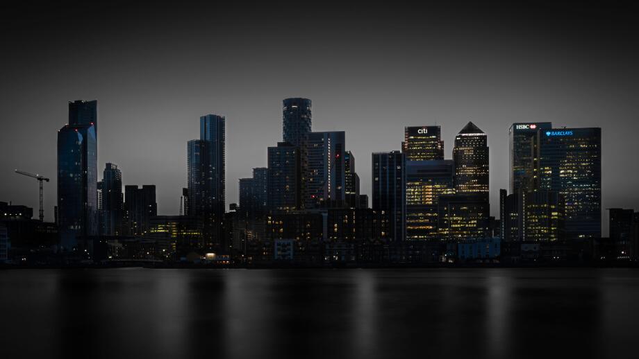 City of London skyline at night with reflected buildings on a smoothed out River Thames.