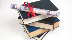 Rolls of twenty pound notes wrapped with red ribbon on a stack of books.Higher earners with degrees,tuition fees.