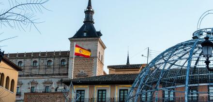 Toledo, Spain - December 23, 2024: A Spanish flag flies atop Alcazar from Zocodover square during christmas time