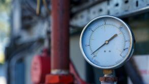 Small industrial analoge pressure guage, with out of focus pipes in the background