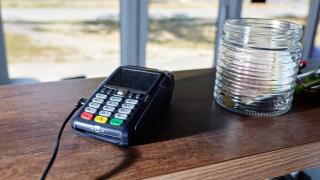 The credit card payment terminal is on the table in coffee shop cafe. Close-up of contactless payment device, card machine
