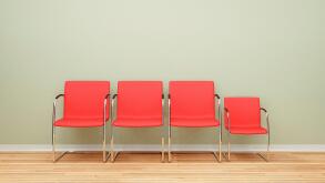 Three larger chairs and one smaller chair in a row in an empty room - difference concept