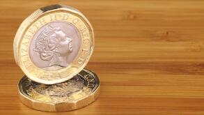 Two new English one pound coins on a wooden background
