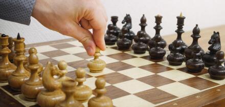 Man's hand making first move in chess game. E2-E4 move. White starts the game.