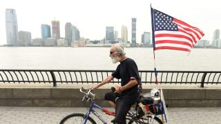 New York, USA - May 28, 2018:  A man with US flag on a bike in Battery Park City Esplanade in New York.