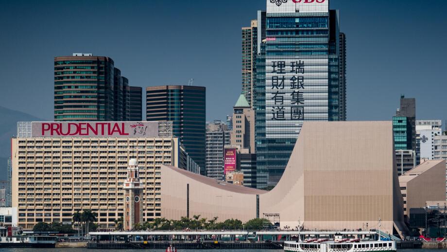 Hong Kong - Star Ferry sails in front of large UBS and Prudential adverts on the Kowloon side of Victoria Harbour