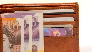 a light brown leather wallet with bank cards and a detailed close-up of credit cards and new plastic GBP £ Sterling Ten and Twenty pound note currency