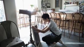 Young woman small business owner preparing menu on cafe blackboard
