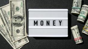 Lightbox board with the word MONEY in black letters around Us dollar banknotes. Finance background. Business, financial success and making money