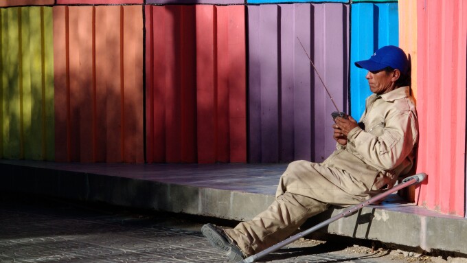 A man listens to a radio while sitting near a colourful monument in Uyuni near the Salar de Uyuni in Boliva