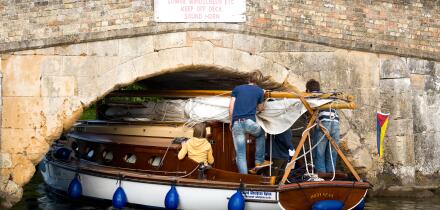 Small yacht carefully navigating the low bridge at Potter Heigham, on the Norfolk Broads, England UK