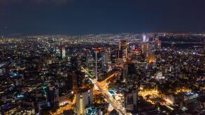 Aerial view of beautiful buildings with illuminated lightings shining in Mexico City against dark black sky at night