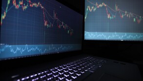 Laptop screen with stock market charts. Technical analysis and fundamental indicators of stock quotes in the trading terminal. Japanese candlesticks and company tickers.