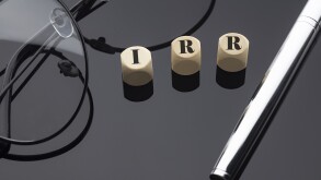IRR concept, words on wooden blocks on the black background with pen and glasses.