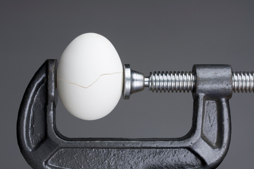 Under pressure.An egg cracking under pressure applied by squeezi