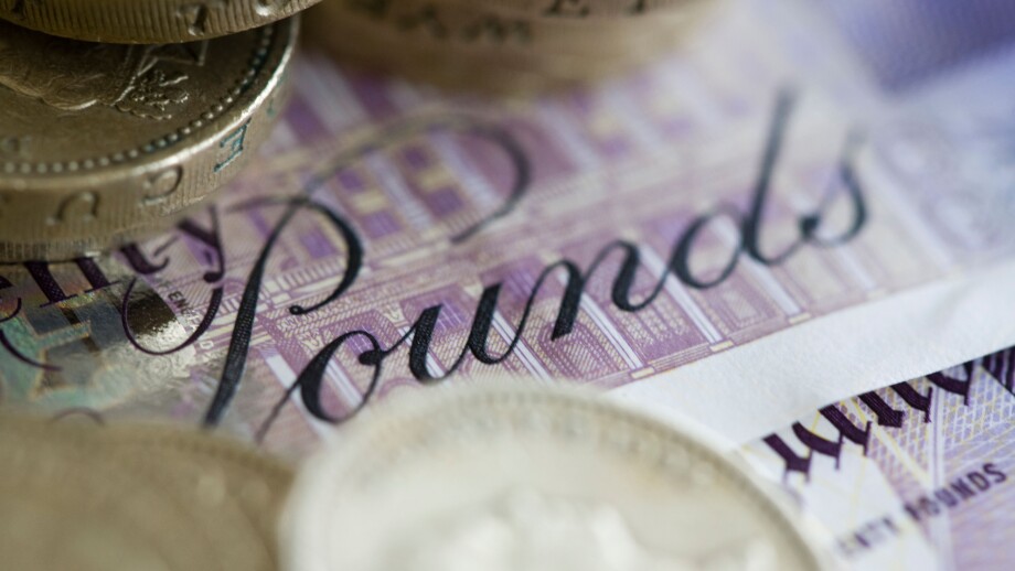 Twenty pound sterling notes and one pound coins are set up for a photograph