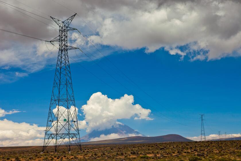 Power lines at Andes in Peru in front of an active volcano