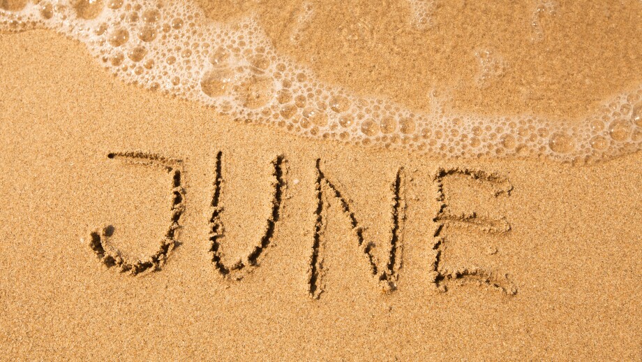 June - written in sand on beach texture, soft wave of the sea