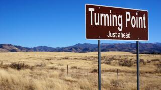 Turning Point Just Ahead  brown road sign with blue sky and wilderness