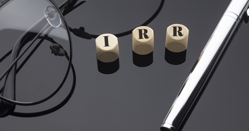 IRR concept, words on wooden blocks on the black background with pen and glasses.