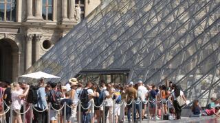 People wait line up near Pyramid at the Louvre Museum during a hot summer day with 30 degrees Celsius on August 25, 2022 in Paris,France.