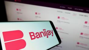 Smartphone with logo of French entertainment company Banijay Group on screen in front of business website. Focus on center-left of phone display.