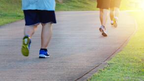 Fat man jogging, catching up with thin men. Low angle view of runners running in park. Blurred feet motion group of runners, Fitness and healthy
