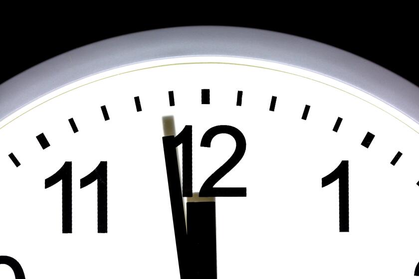 Close up of a clock showing one minute to 12, midnight.