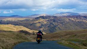 Man on motorbike descending the Honister Pass (B5289), Lake District National Park, Cumbria, England UK