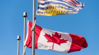 Canada and British Columbia flags waving over blue sky in Vancouver, BC, Canada