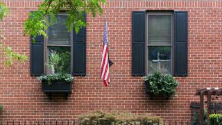 Philadelphia, USA ? July 20, 2013:
A brick townhouse with black shutters, window boxes, and an American flag on a quiet street in Philadelphia.