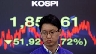 A foreign currency dealer from the Korea Exchange Bank walks past a screen displaying the Korea Composite Stock Price Index (KOSPI) at the bank's dealing room in Seoul November 10, 2011. Seoul shares tumbled on Thursday as a spike in Italian bond yields s