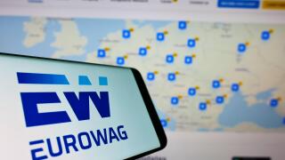 Mobile phone with logo of payment company W.A.G. payment solutions (Eurowag) on screen in front of website. Focus on center-right of phone display.
