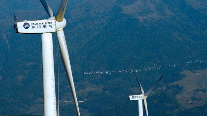--FILE--Wind turbines manufactured by Mingyang Electric whirl to generate electricity at a wind farm on the outskirts of Xinyi city, south China's Gua
