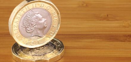 Two new English one pound coins on a wooden background