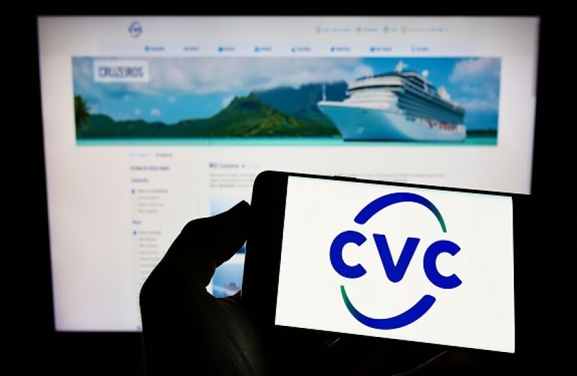Person holding cellphone with logo of company CVC Brasil Operadora e Agencia de Viagens SA on screen with business webpage. Focus on phone display.
