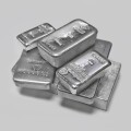 Silver bullion bars in a pile on plain grey background