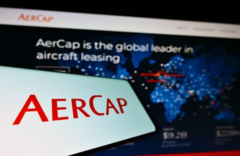 Cellphone with logo of aircraft leasing company AerCap Holdings NV on screen in front of business website. Focus on center-left of phone display.
