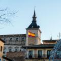 Toledo, Spain - December 23, 2024: A Spanish flag flies atop Alcazar from Zocodover square during christmas time