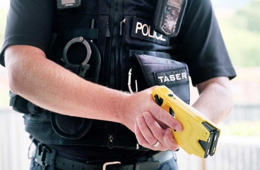 A British police officer holding a axon taser X2 conducted electrical weapon or stun gun. The taser is routinely issued to police forces across the uk