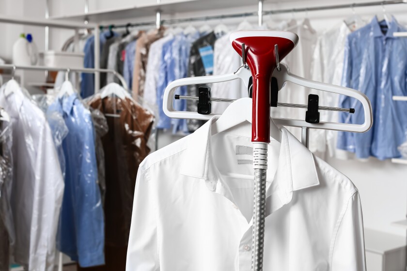 Rack with clothes and steamer in modern dry-cleaner's 575