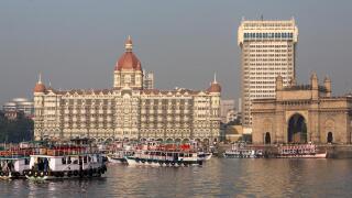 Mumbai waterfront from harbor with skyline, excursion boats, Gateway of India arch and Taj Mahal Palace Hotel
