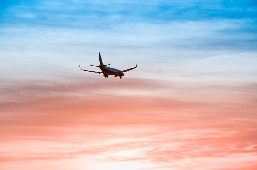 Large plane flies in the evening sunset sky, dramatic painted sky and airplane silhouette with clouds over Lisbon in Portugal