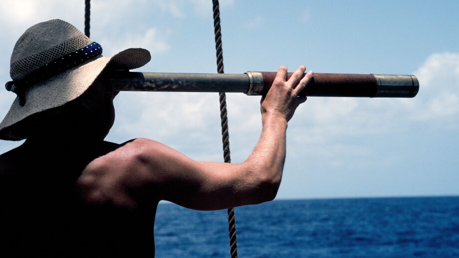 A young man with a long telescope is literally "looking to the future" as he scans the sea from the deck of an old sailing ship in the Caribbean Sea.. Image shot 2009. Exact date unknown.