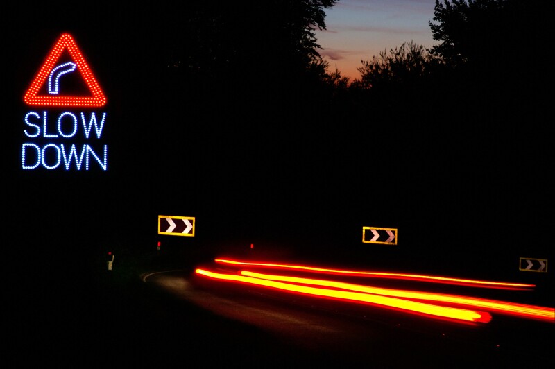 dangerous drive and speeding at night on the hairpin bend road. Slow DOWN sign